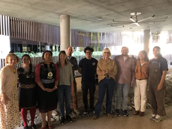 A group of nine colleagues stand in a row smiling